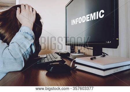 Coronavirus Infodemic Concept. Frightened Woman Sitting In Front Of Computer Monitor With Text Infod