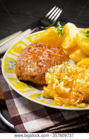 Minced Pork Cutlet Served With Potatoes And Sauerkraut Salad.