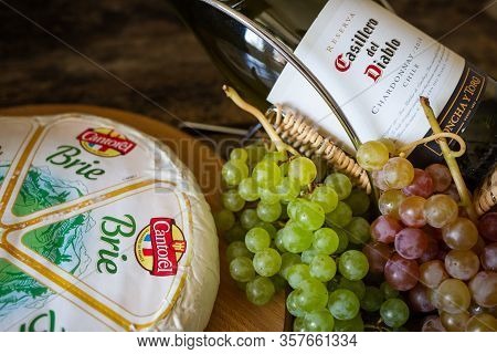 Cheese Brie With Bottle Of Chardonnay Of Casillero Del Diablo With Bunch Of Grapes On The Table