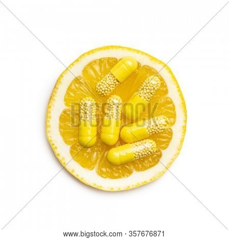 Vitamin capsules. Vitamin C pills and slice of lemon isolated on white background. Top view.