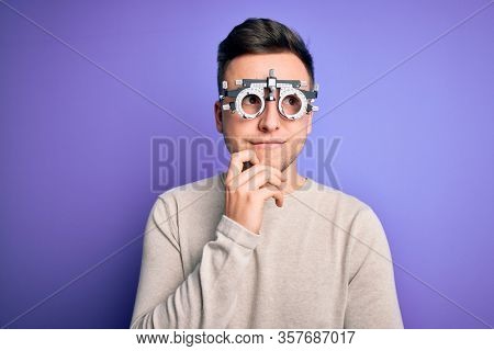 Young handsome caucasian man wearing optometrical glasses over purple background with hand on chin thinking about question, pensive expression. Smiling with thoughtful face. Doubt concept.