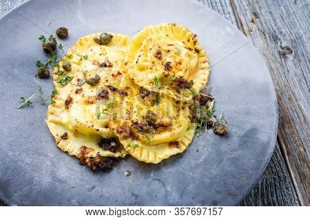 black, yellow, decorated, pattern, close-up, textureTraditional Italian ravioli pasta offered with capers and onion chili pesto closeup on a modern design plate 