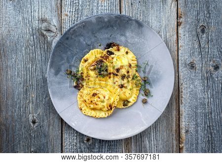 Traditional Italian ravioli pasta offered with capers and onion chili pesto as top view on a modern design plate with copy space 