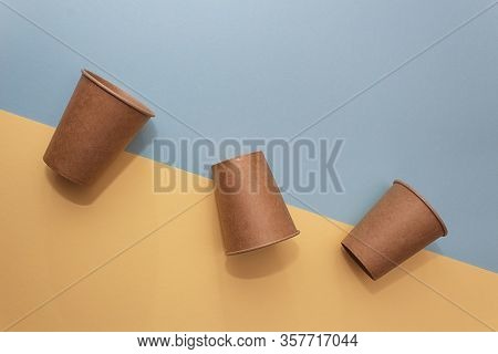 Three Craft Paper Cups For Coffee Or Any Drinks On A Blue And Yellow Paper Background. Concept Of Zi