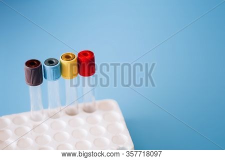 Empty Test Tubes With Colorful Caps In A Tray On A Blue Background