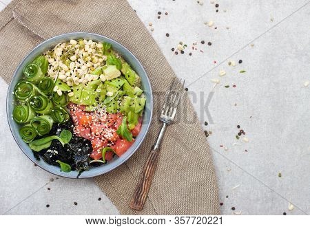 Salted Salmon Poke Bowl With Avocado, Sea Cale, Cucumber, Sesame Seeds And Bean Sprouts On Grey Back