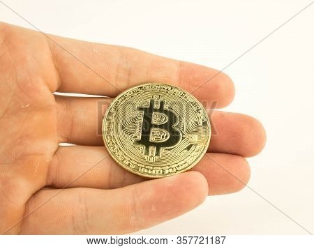 Gold Bitcoin Coin In A Mans Hand On A White Background