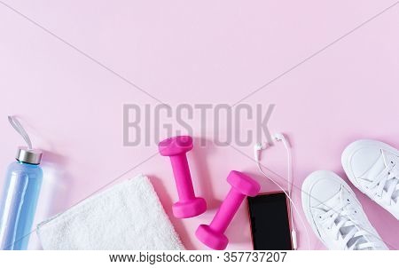 Fitness Equipment Top View With Copy Space. Dumbbells, Towel, Sneakers And Isotonic Drink On Pink Ba