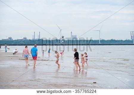 Hoek Van Holland, Netherlands - May 21, 2018: People Enjoying The Sandy Beach With The Entrance Of T