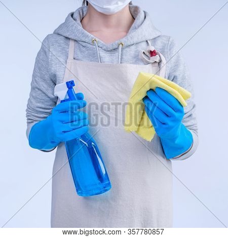 Young Woman Housekeeper In Apron Is Doing Cleaning With Blue Gloves, Wet Yellow Rag, Spraying Bottle