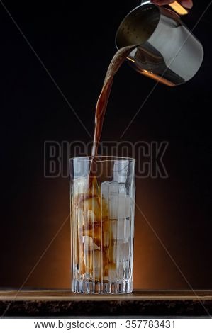 Iced Wspresso With Dark Background On A Wooden Table. Fresh Coffee Pouring In A Glass Filled With Ic