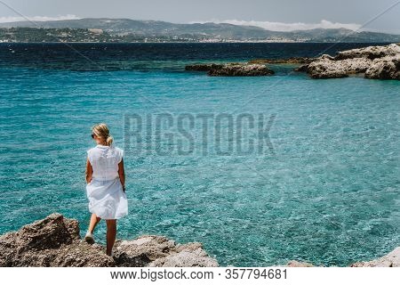 Adult Female In White Dress On Summer Vacation Enjoying Sea Coast Landscape Of Small Beach With Crys