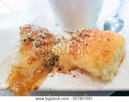 Delicious Greek sweet pastry named Galaktoboureko, made of semolina custard in filo, served with honey in white plate.