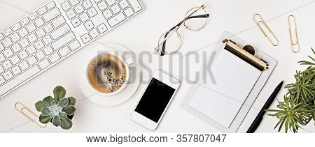 Top View Of Office Desk. Table With Keyboard, Smartphone, Clipboard And Office Supplies. Flat Lay Ho