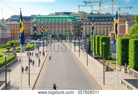 Sweden, Stockholm, May 29, 2018: Riksplan Green Grass Lawn, Bushes And Street With National Flags On