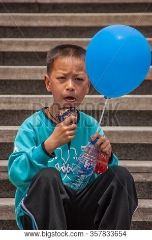 Shanghai, China - May 4, 2010: Closeup Of Boy Wearing Azure Shirt, Holding Blue Balloon On Side Of H