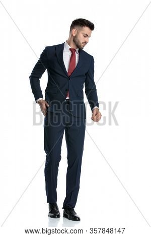 young businessman wearing navy suit walking with hand in pocket and looking aside dramatic on white studio background