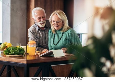 Happy Retired Couple Browsing The Internet Together On Digital Tablet.quarantine. Health Concept.