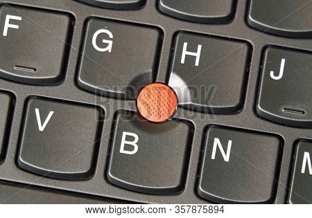 Red Trackpoint On A Laptop Keyboard. A Pointing Stick Is A Small Joystick Used As A Pointing Device 