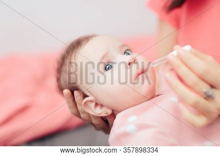 Mother Administrating Vitamin D Medicine To Her Baby