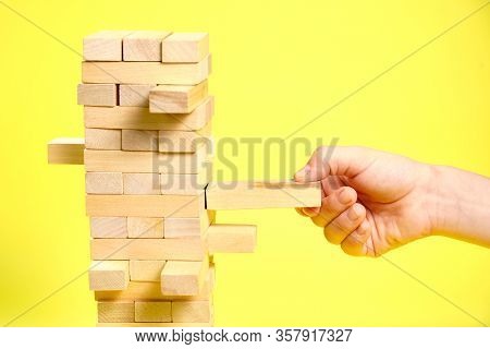 Blocks Of The Wooden Game Jenga On A Yellow Background, Space For Text