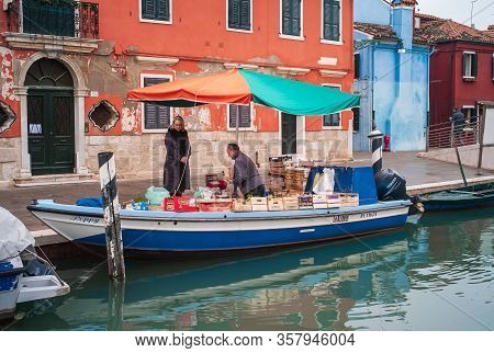 Burano, Venice, Italy - January 3 2014: Woman Buying Groceries From A Boat In Venice. Groceries Boat