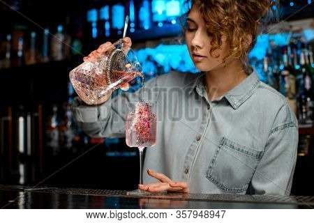 Lady Barman Carefully Pours Pink Cocktail From Large Glass Into Wineglass.