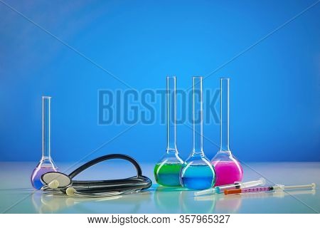 Four Medical Flasks With Colorful Chemical Reagents. Testing Kit, Syringe And Phonendoscope, Blue Ba