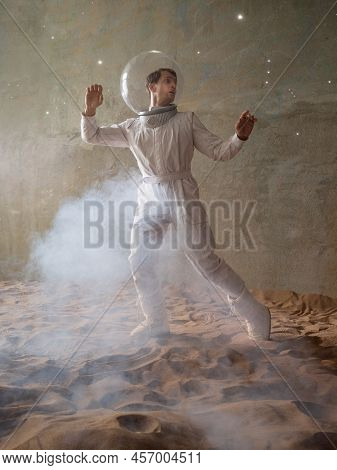 Fear Of The Unknown On Alien Planets. An Astronaut In A White Spacesuit Walks Through An Abandoned C