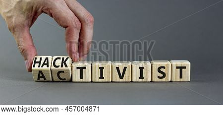 Activist Or Hacktivist Symbol. Businessman Turns Wooden Cubes And Changes The Word Activist To Hackt