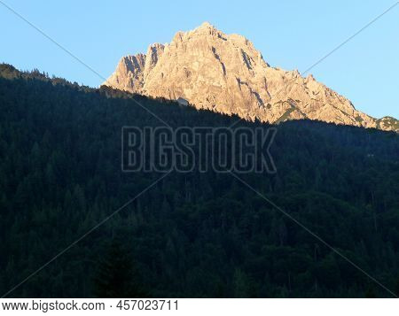 The Evening Sun Is Shining At A Mountaintop.