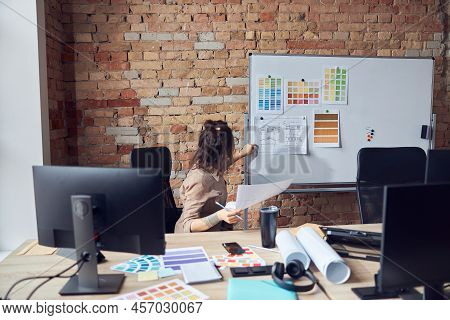 Woman Designer Attaching Blueprint Paper And Color Samples On Board While Working On New Interior De