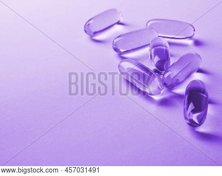 Fish Oil Softgels Lie On A Light Surface. Vitamin And A Healthy Lifestyle. Purple Tinted Background 