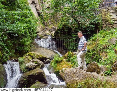Makhuntseti, Georgia. 06.24.2022 Man On A Rock Near A Stream. Rapids On The River. Shallow River Wit