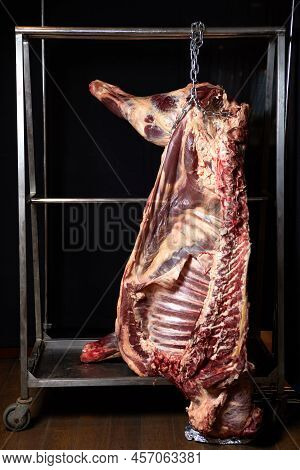Beef Carcass Hanging On A Black Background