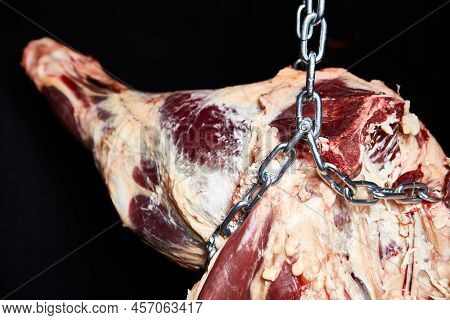 Beef Carcass Hanging On A Black Background
