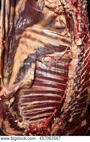 Beef Carcass Hanging On A Black Background