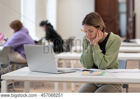 Upset Female Mature-age Student Sitting At Desk With Laptop In Classroom, Tired Of Studying. Pensive