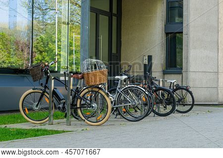Bicycles Standing Near The Administrative Building. Wicker Korb On The Trunk.