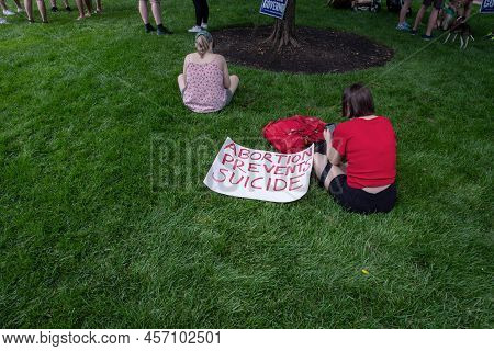 Philadelphia, Pa Usa - 06-25-2002 Woman At A Political Pro-choice Rally Sits In The Grass Next To A 