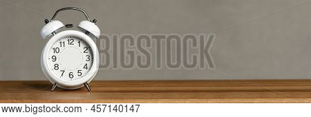 Alarm Clock Without Arrows. White Classic Alarm Clock On A Wooden Background Without Hands, Space To