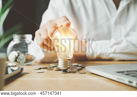 Businessman Holding Lightbulb On Coins Stacking On Desk With Note For Planning Money Finance.saving 