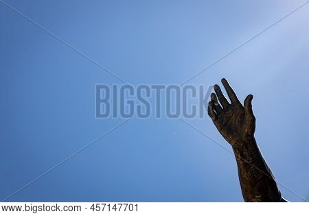 Hand Pointing To The Sky From A Metal Statue. Free Space To Write.