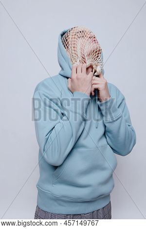 Tortured, Suffering From Problems, A Man With A Mesh On His Face Stands In A Light Blue Hoodie On A 