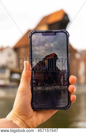 Traveler Taking Photo Of Ancient Crane - Zuraw Old Town In Gdansk. The Riverside On Granary Island R