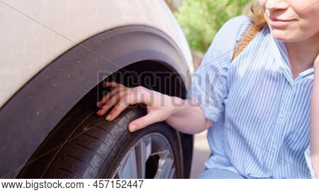 The Woman Inspects The Puncture Site On The Flat Tire Of The Car. Tire Service