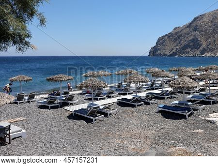 Kamari, Santorini, Greece - June 30, 2021: Sun Loungers On The Black Volcanic Beach Of Kamari In San