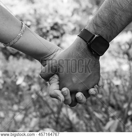 Indian Couple Posing For Maternity Baby Shoot. The Couple Is Posing In A Lawn With Green Grass And T