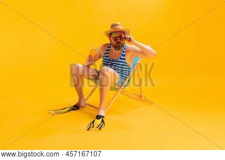 Studio Shoot Of Cool Funny Beachgoer, Man In Vintage Striped Swimsuit And Bowler Hat Sitting In Sunb