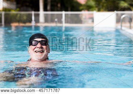 Senior Bearded Man Having Fun In Outdoor Swimming Pool, Happy For Healty Activity Wearing Black Swim
